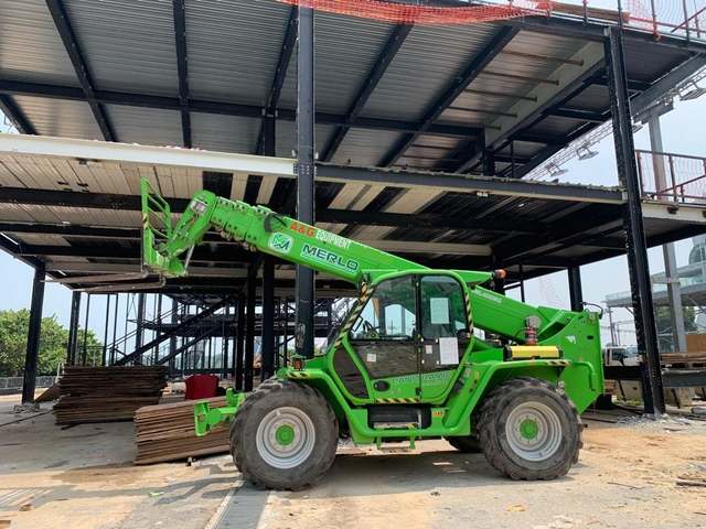 Merlo Panoramic telehandler with boom raised beside a steel-frame building under construction – telehandler rental in Johor